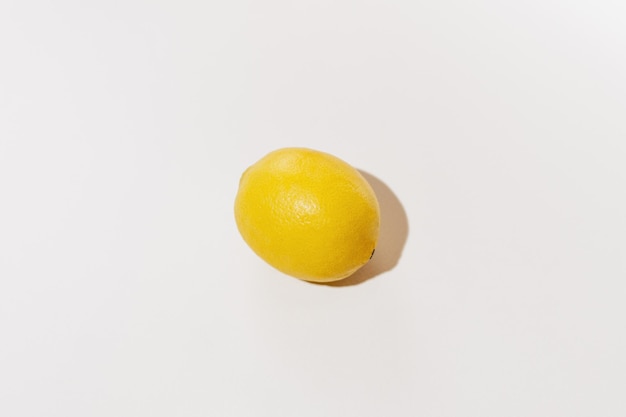 Limón amarillo iluminado por la dura luz del día sobre un fondo blanco aislado Imagen para su diseño Ingrediente para cometas