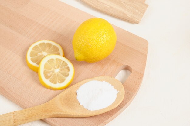 Limón y bicarbonato de sodio en una cuchara de madera, tabla de tejer en el espacio de copia de fondo beige