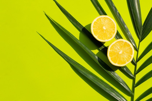 Limón fresco con hojas de palmera en superficie verde