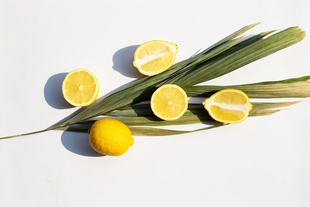 Limón fresco con hojas secas sobre superficie blanca