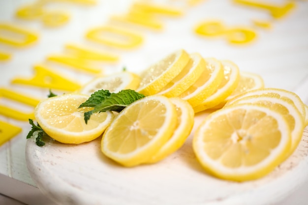 Limón fresco en rodajas sobre una tabla de cortar de madera blanca.