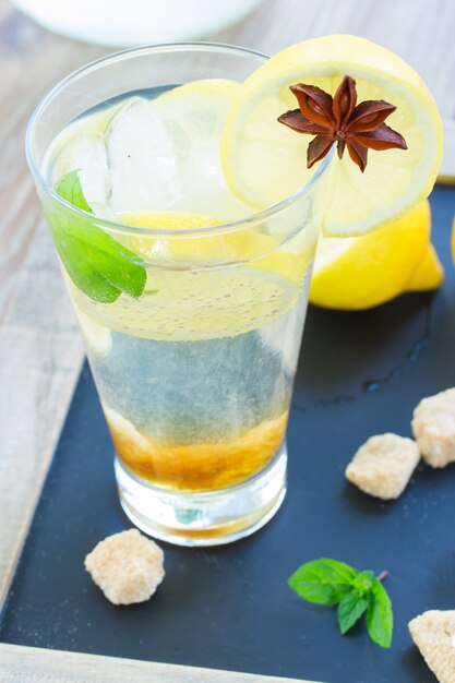 Limón fresco en vaso alto sobre mesa de madera