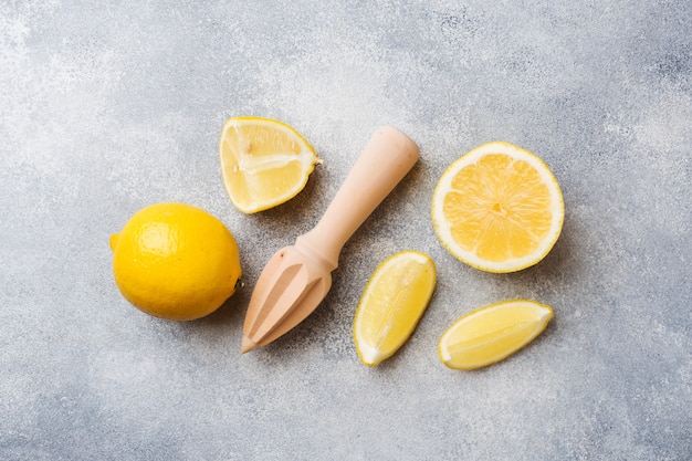 Limón maduro y rodajas de limón sobre superficie gris.