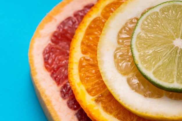 Foto limón, naranja, lima y pomelo sobre un fondo azul.