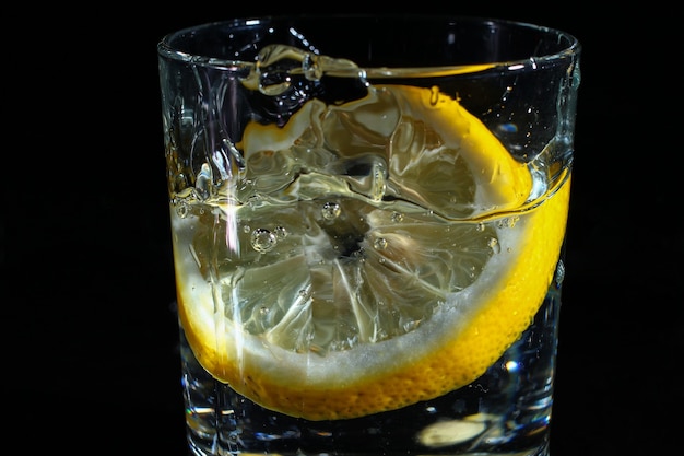 Limón en un vaso de agua sobre un fondo negro oscuro