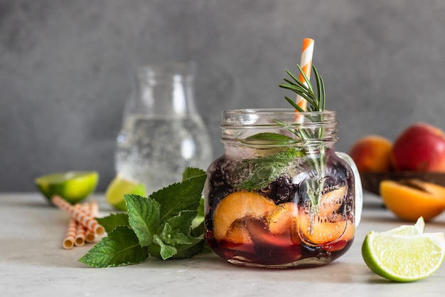 Limonada de albaricoque y grosella negra en vaso con albaricoque, romero, menta y lima.