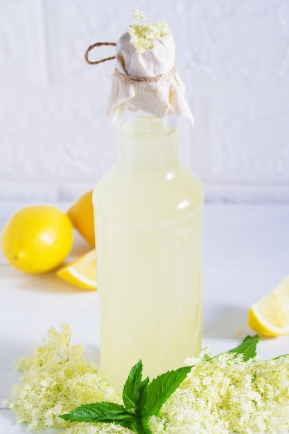 Limonada de ancianos bebida saludable y refrescante de verano. Ciérrese para arriba del jarabe casero de la flor del saúco en una botella con las flores más viejas. Bebida de verano Hugo Champagne bebida con jarabe de flor de saúco, menta y lima.