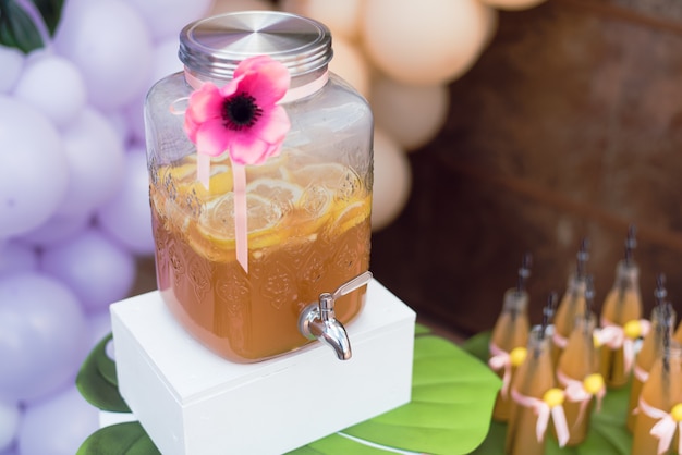 Limonada caseira de limão na festa de aniversário. Suco em uma jarra de vidro com uma torneira e garrafas com canudos