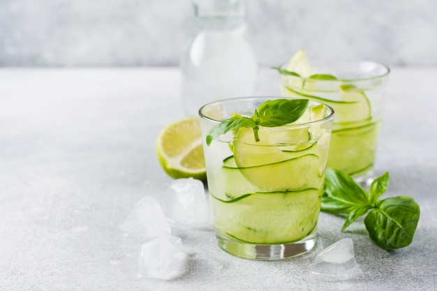 Limonada caseira de verão feita de limão, limão, pepino e manjericão com gelo em um copo em um concreto velho.