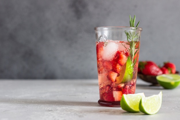 Limonada casera de fresa en vidrio con fresas frescas, romero, granada y limón.