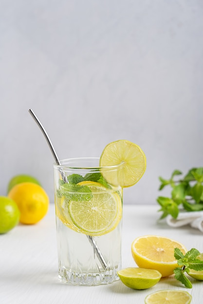 Limonada casera orgánica dulce hecha de rodajas de limón y lima madura agria servida en vaso con paja