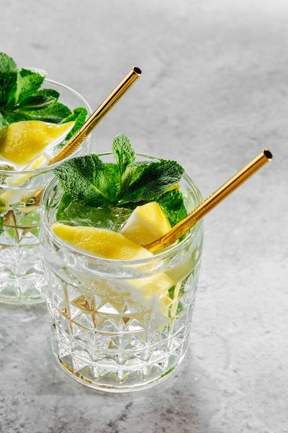 Limonada casera en vasos elegantes con paja dorada sobre fondo de mármol blanco