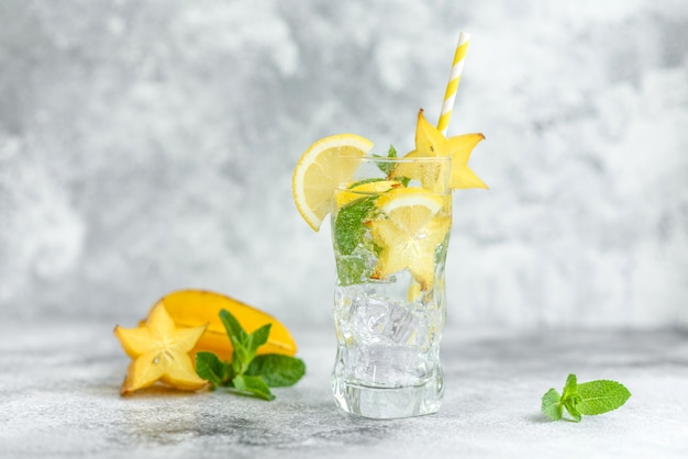 Limonada com limão, hortelã e cubos de gelo em vidro na parede de pedra cinza