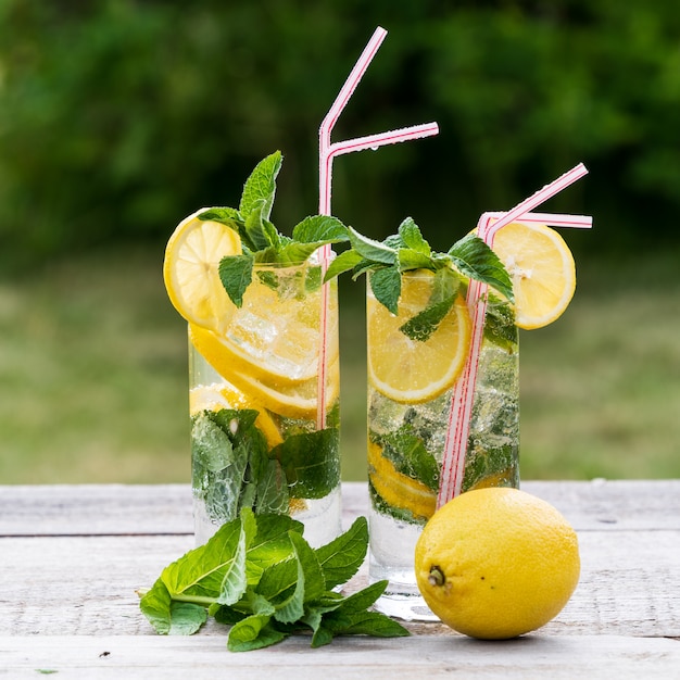 Limonada com limão, hortelã e gelo, em copos, mais velha mesa de madeira