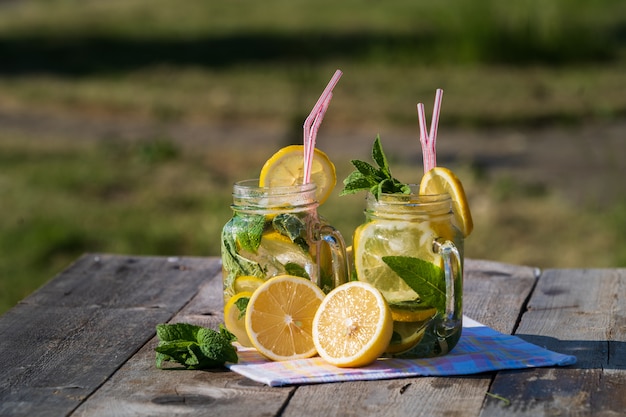 Limonada com limão, hortelã e gelo, em um óculos, mesa de madeira velha, ao ar livre.