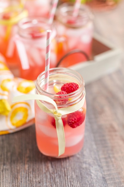 Limonada de framboesa guarnecida com limão fresco e framboesas em potes de pedreiro.