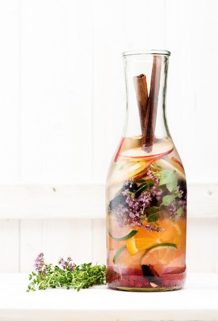Limonada de frutas de verão em uma garrafa de vidro em uma mesa de madeira clara
