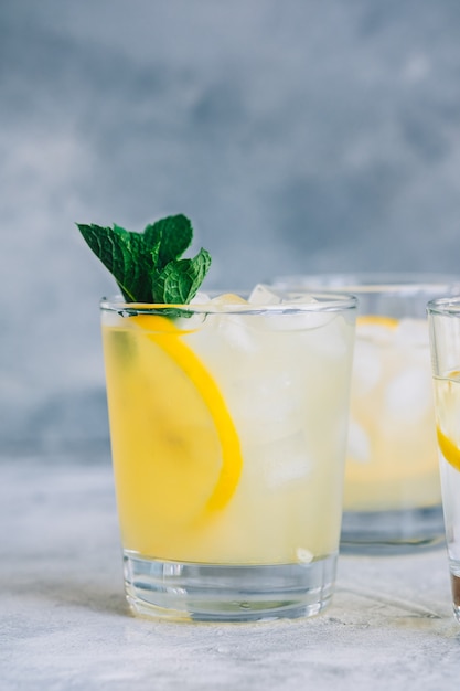 Limonada de gelo em copo com pedaços de limão, hortelã fresca e cubos de gelo.