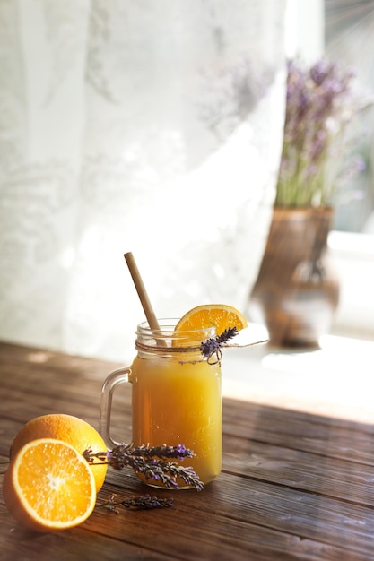 Limonada de laranja em uma caneca em uma mesa de madeira perto da janela