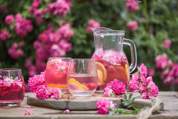 Limonada de rosas frescas com gelo e rosas frescas sobre jardim natural