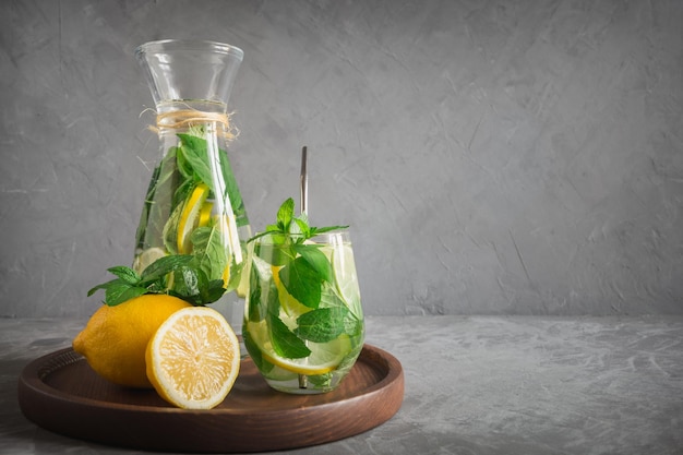 Limonada de desintoxicación con cítricos de menta en vidrio sobre fondo gris