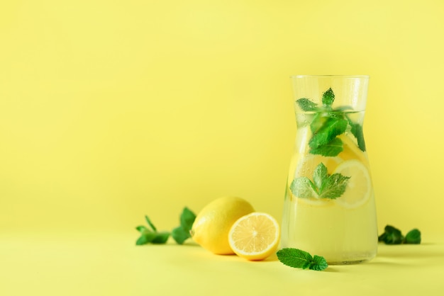 Limonada do citrino - água fria com gelo, hortelã, limão no fundo amarelo. Bebida de desintoxicação.