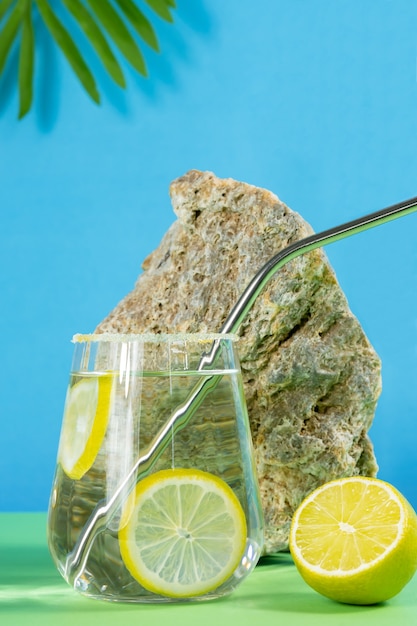 Limonada em fundo verde azulado com folha de palmeira pedra e limão closeup