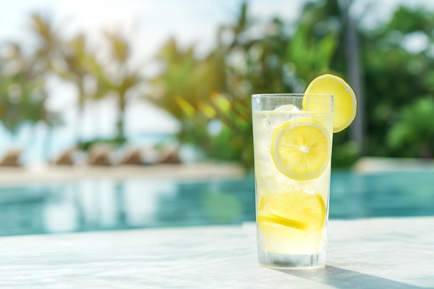 Limonada em um copo em superfície de concreto branco contra o fundo de um hotel tropical de luxo