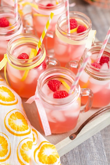 Limonada de frambuesa adornada con limón fresco y frambuesas en tarros de albañil.