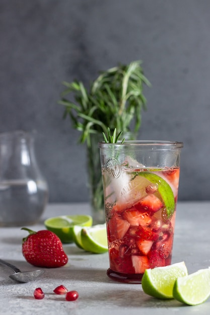 Limonada con fresas, romero, granada y lima. Bar de cócteles de fondo.