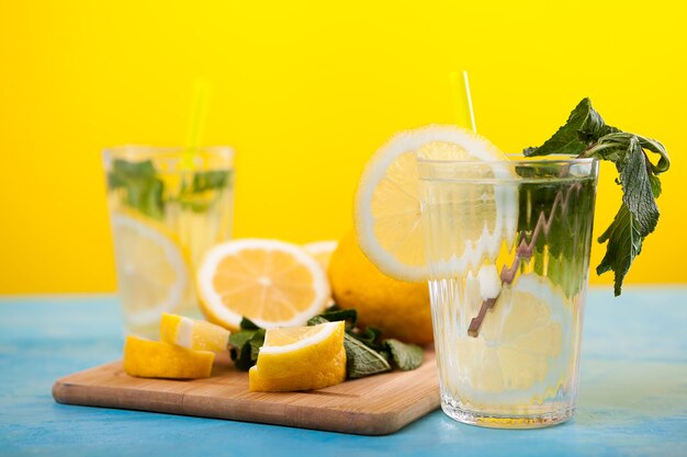 Limonada fresca caseira em dois copos ao lado de limões orgânicos em uma placa de madeira