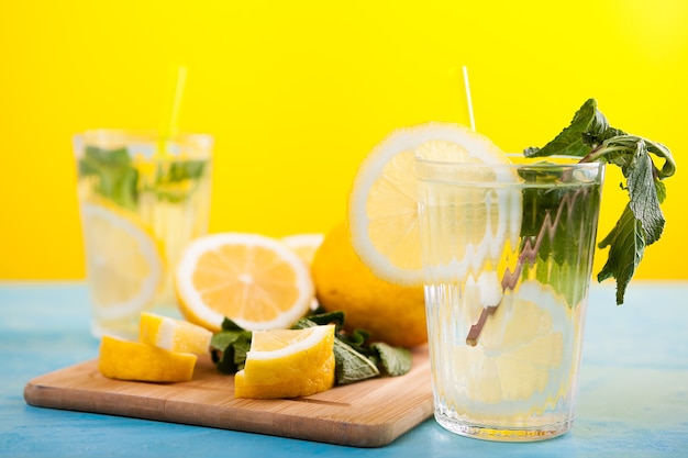 Limonada fresca caseira em dois copos ao lado de limões orgânicos em uma placa de madeira