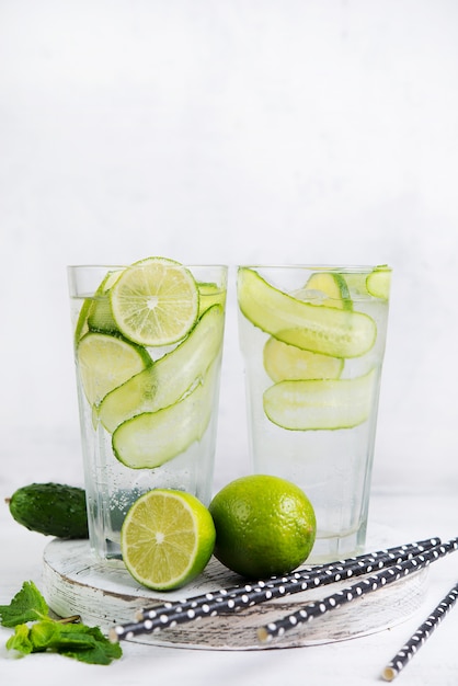 Limonada fría casera con limón, lima, pepino y menta en una pared blanca.