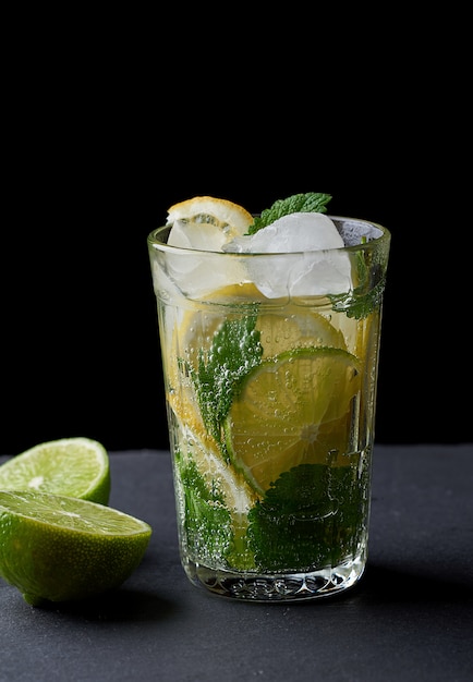 Limonada fría hecha de limones frescos, lima, menta verde y trozos de hielo en un vaso