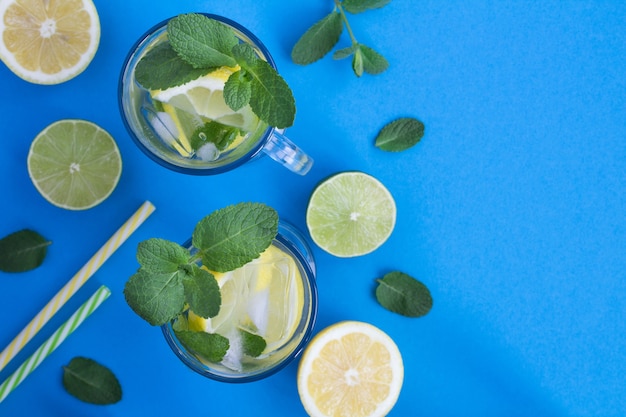 Limonada fría con limón y menta en los vasos sobre el fondo azul.Vista superior. Copiar el espacio.