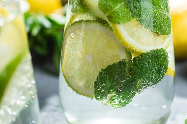 Limonada fría con menta, limón y lima en un vaso. preparación de limonada