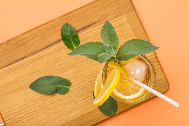 Limonada fría y refrescante de verano con hielo y rodajas de limón decoradas con hojas de menta en un vaso alto