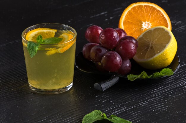 Limonada gelada fresca com fatias de uva na mesa escura