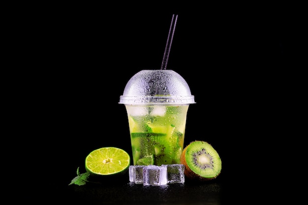 Limonada para ir taza con menta, limón y kiwi en espacio negro, aislado