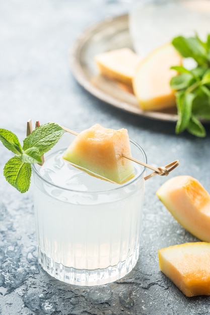 Limonada de melón con hielo y menta en un vaso sobre la mesa gris bebida refrescante de verano