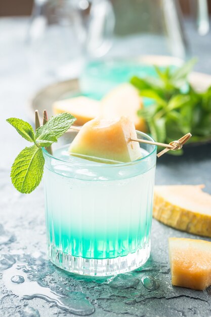 Limonada de melón con hielo y menta en un vaso sobre la mesa gris bebida refrescante de verano