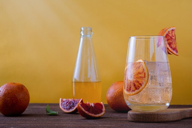 Limonada de naranja fresca hecha de naranjas frescas Limonada natural a base de jugo de naranja sin azúcar copyspace Limonada de naranja roja casera sobre un fondo amarillo brillante Foto horizontal