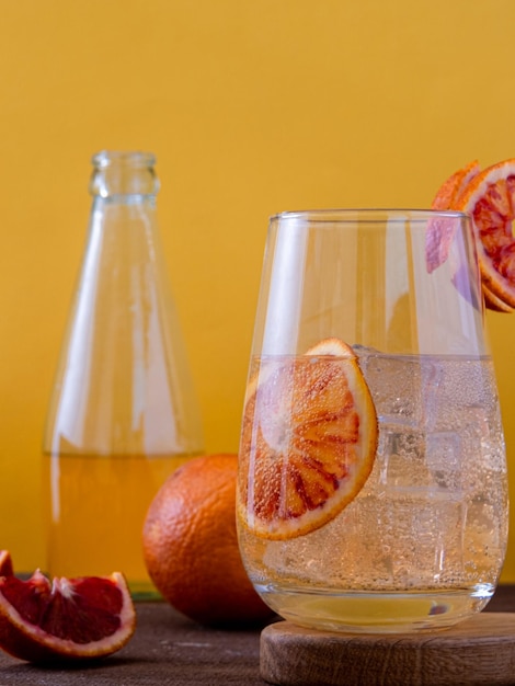 Limonada de naranja fresca hecha de naranjas frescas Limonada natural a base de jugo de naranja sin azúcar Nutrición adecuada Limonada de naranja roja casera sobre un fondo amarillo brillante