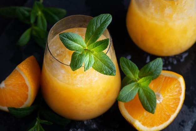 Limonada de naranja de verano frío con menta y hielo en un vaso