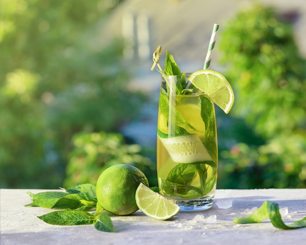 Limonada o cóctel mojito con lima, pepino y menta, bebida refrescante fría o bebida con hielo, al aire libre. Agua fría de desintoxicación con limón y paja de papel. Bebida de verano con espacio de copia.