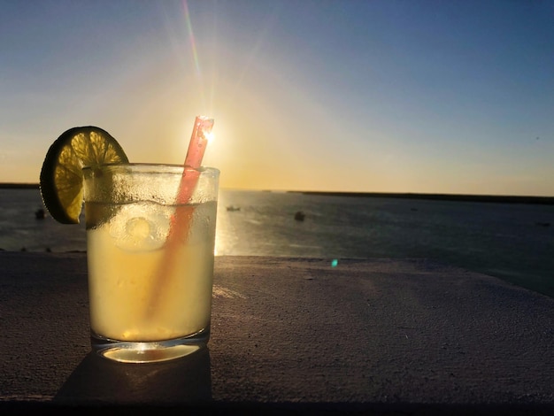 Foto limonada en la playa contra el cielo durante la puesta de sol