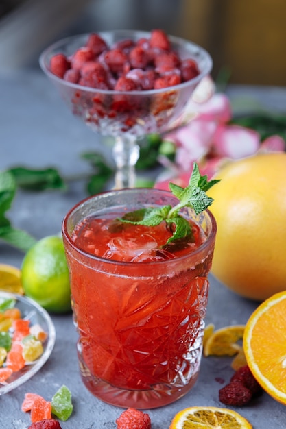 Limonada rosa fresca con frambuesas decorada con hojas de menta, limón naranja y frutas confitadas