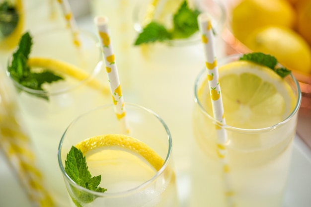 Limonada tradicional con una rodaja de limón fresco y menta con pajita de papel en el vaso.