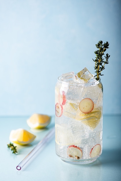 Limonada con trozos de uva y hielo en un vaso alto sobre un fondo azul.