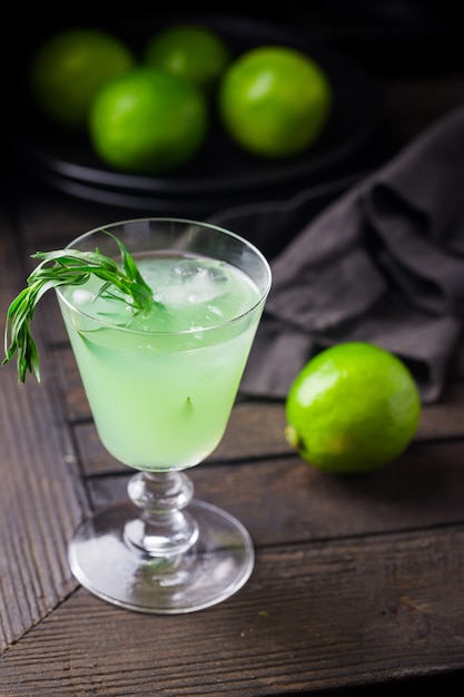 Limonada verde brillante con estragón y bebida refrescante de lima con hielo sobre negro